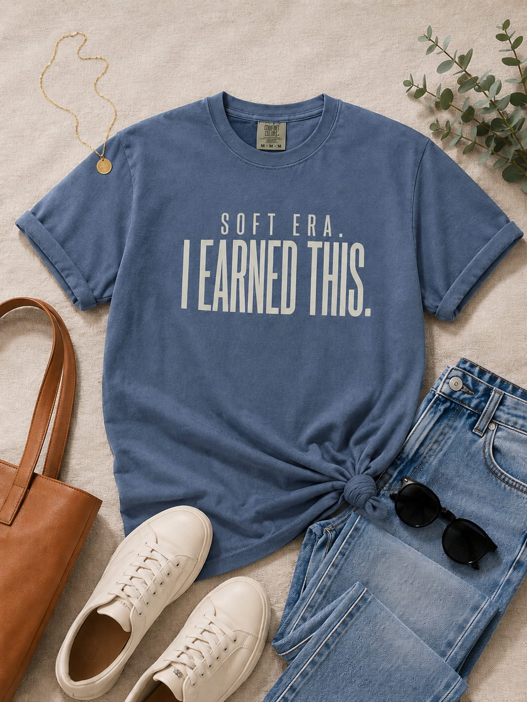 Woman wearing the Soft Era I Earned It tee in an elevated casual outfit