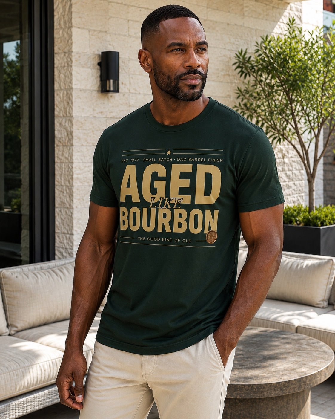 Male model wearing the personalized Aged Like Bourbon forest green tee on a premium outdoor patio