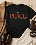 Styled flat lay of the At Peace Still Paying Attention Comfort Colors Black statement tee with a camel blazer, cream trousers, brown loafers, and gold jewelry.