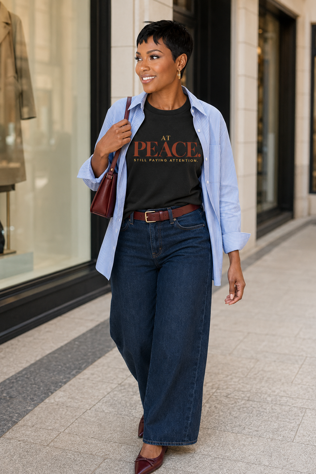 Black woman wearing the At Peace Still Paying Attention Comfort Colors Black statement tee with layered blue shirting and wide-leg denim.