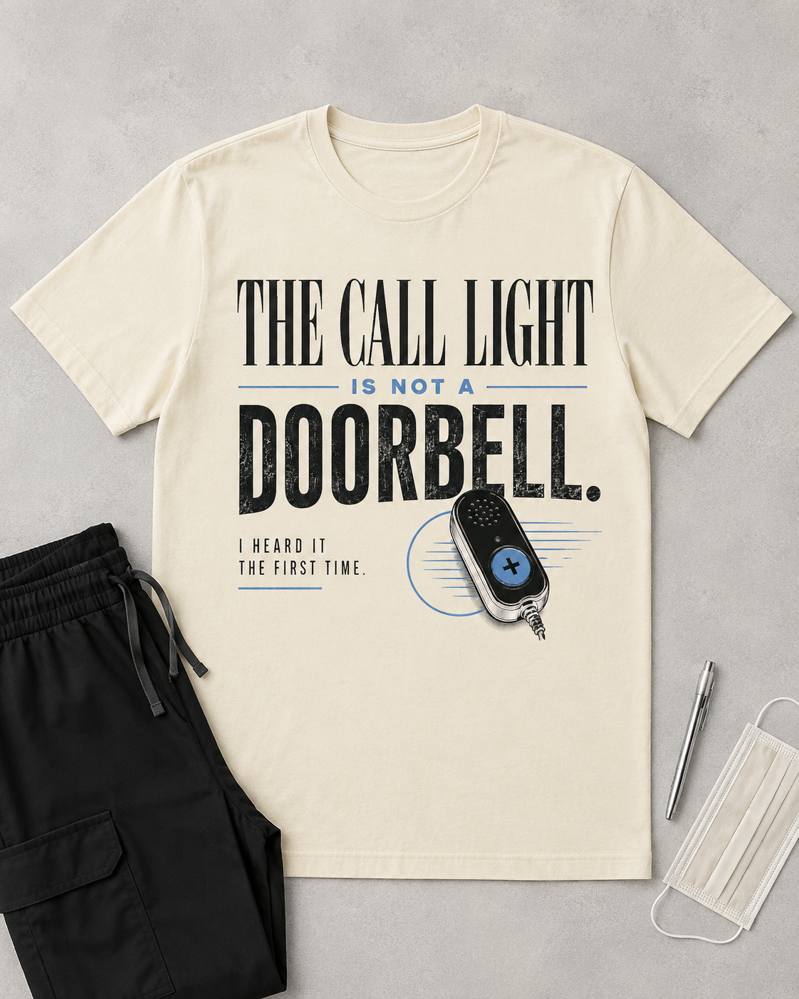 Ivory Call Light Is Not a Doorbell nurse tee flat lay with black scrub pants and penlight