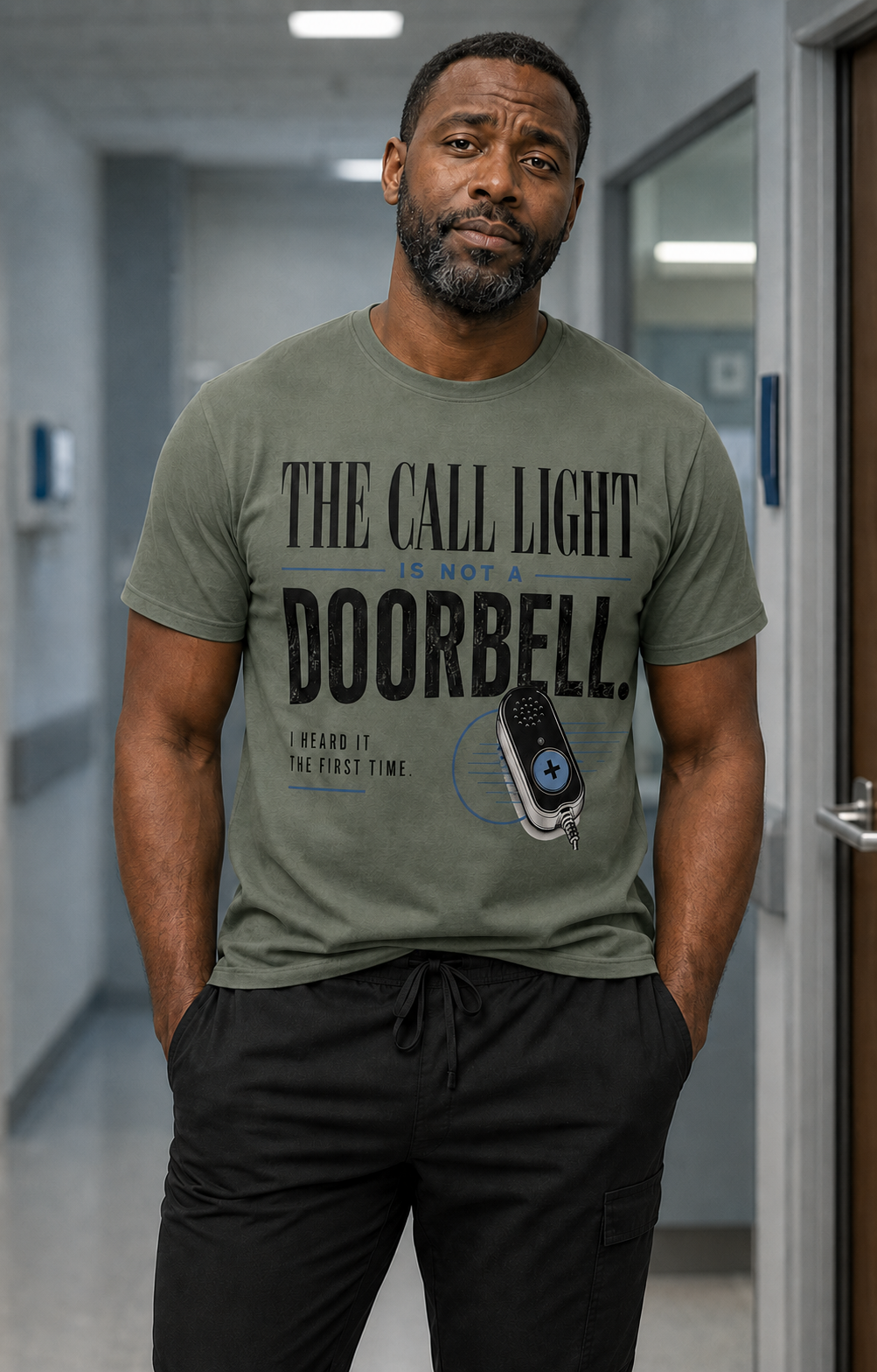 African American male nurse wearing Comfort Colors Sage Call Light Is Not a Doorbell tee with black scrub pants