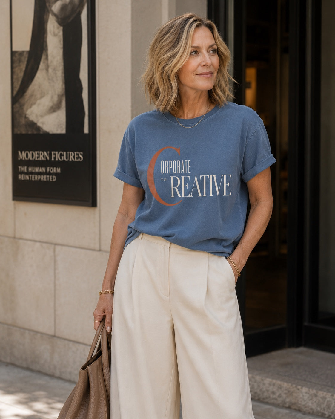 Woman wearing the Corporate to Creative statement tee in Comfort Colors Blue Jean outside a modern gallery