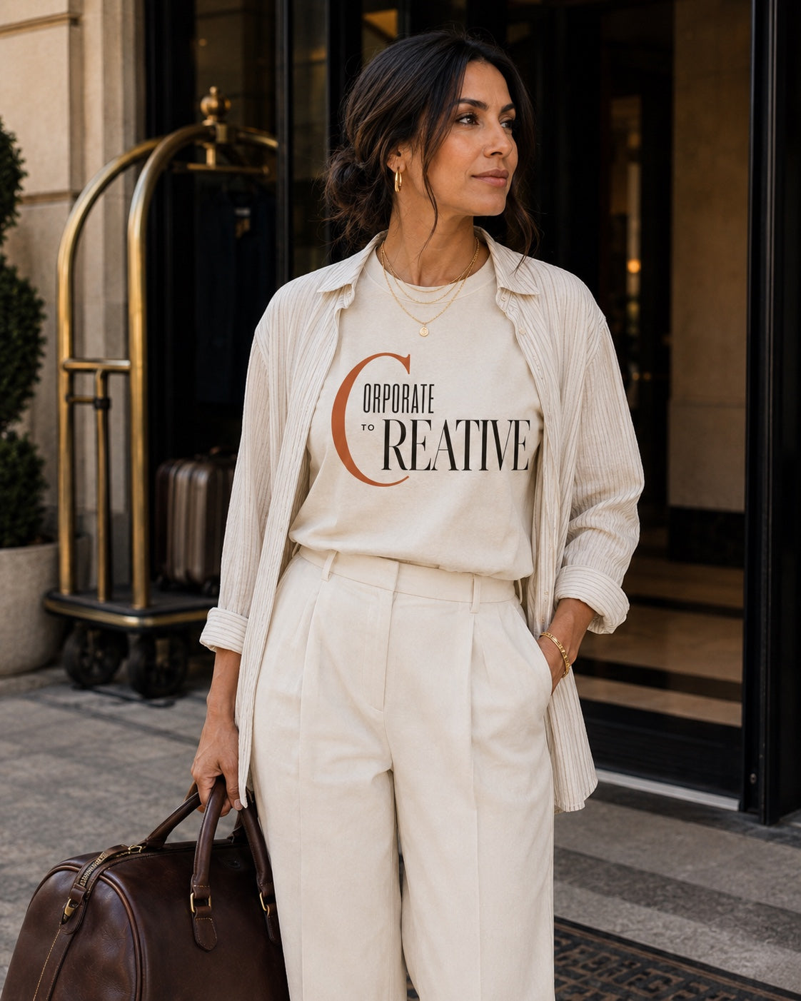 Woman wearing the Corporate to Creative statement tee in Comfort Colors Ivory with a layered monochromatic travel look
