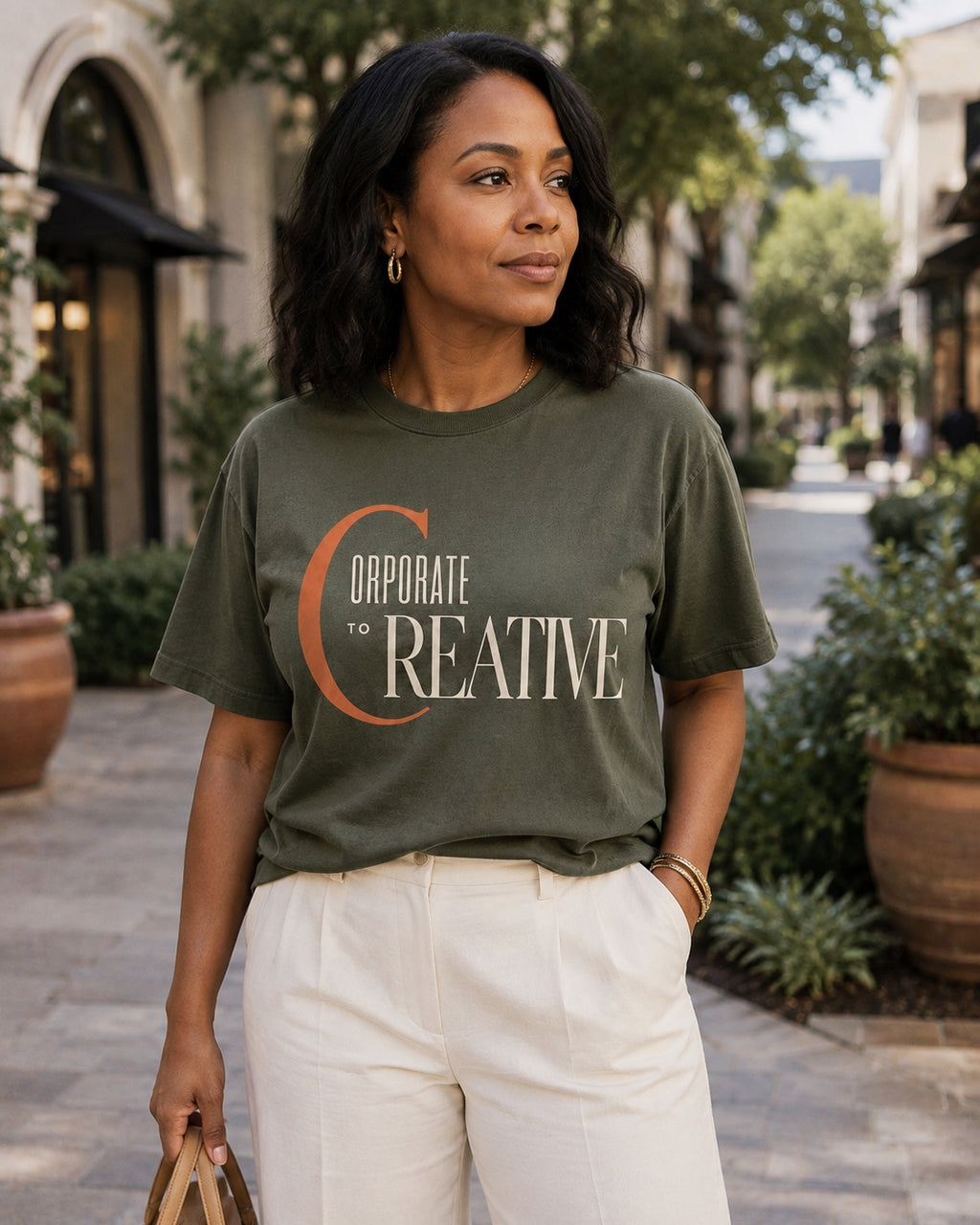 Woman wearing the Corporate to Creative statement tee in Comfort Colors Moss in an open-air shopping district