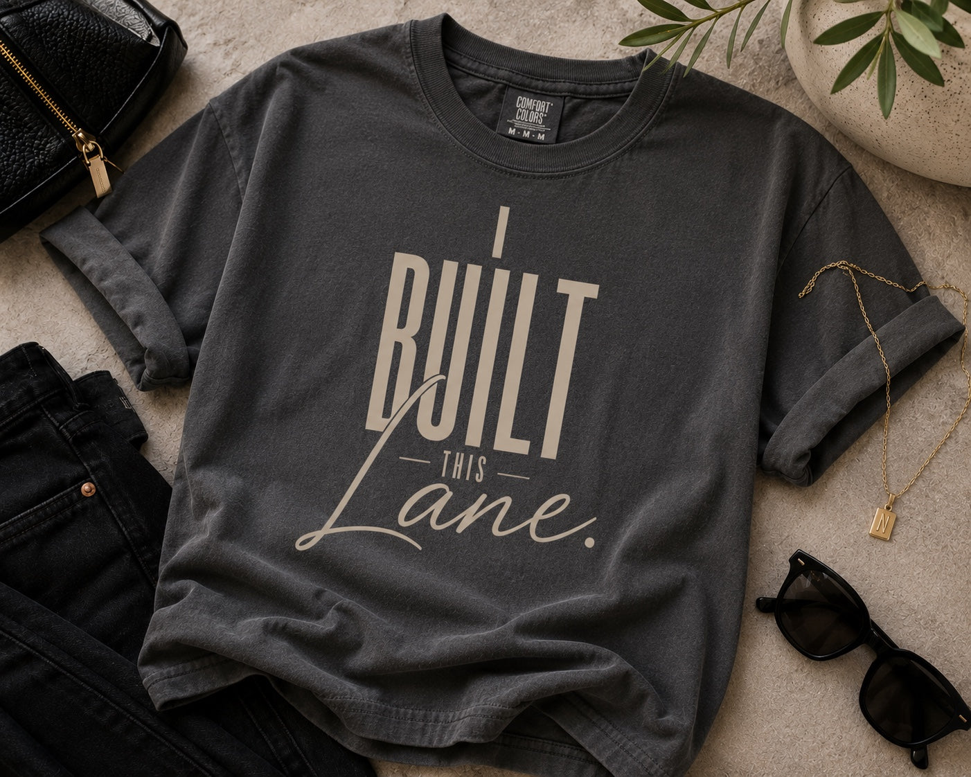 I Built This Lane pepper gray statement tee flat lay with black denim and gold accessories