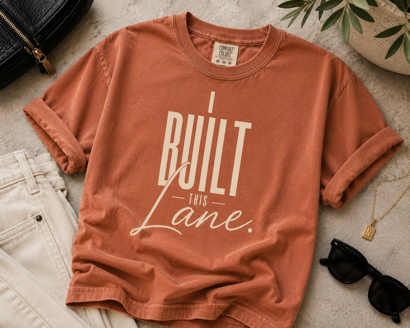 I Built This Lane terracotta statement tee flat lay with neutral accessories