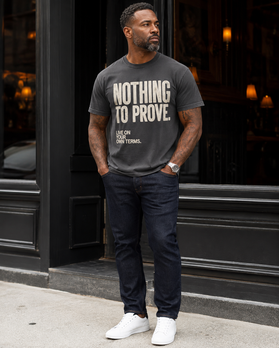 Man wearing Pepper gray Nothing to Prove men's statement tee with dark denim outside a lounge