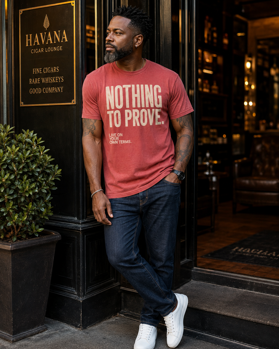 Man wearing red Nothing to Prove men's statement tee with dark denim outside a cigar lounge