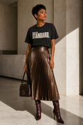 Black woman wearing the Peace Is the Standard Comfort Colors Black statement tee styled with a metallic bronze pleated skirt and oxblood boots.