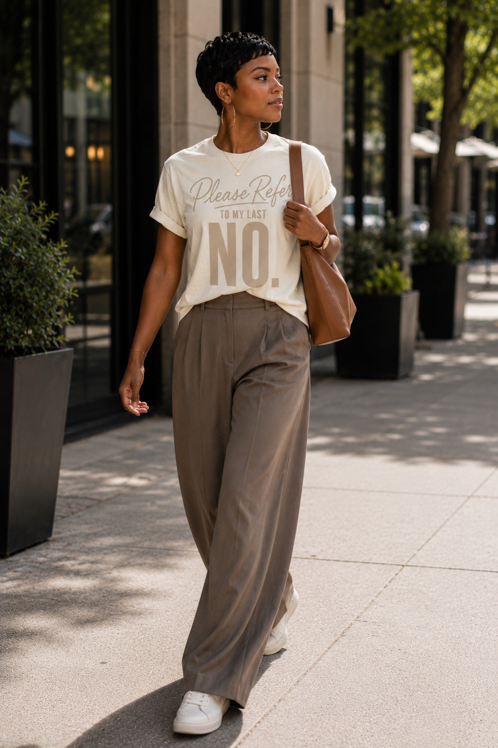 Woman walking in the Please Refer to My Last No. Comfort Colors Ivory tee with wide-leg trousers and white sneakers.
