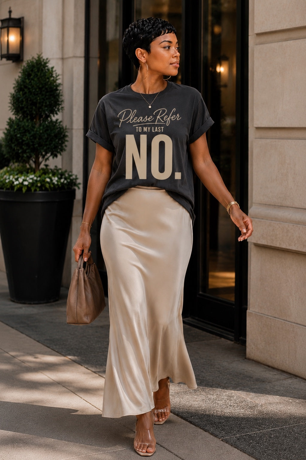 Woman wearing the Please Refer to My Last No. Comfort Colors Pepper tee with an ivory satin skirt.