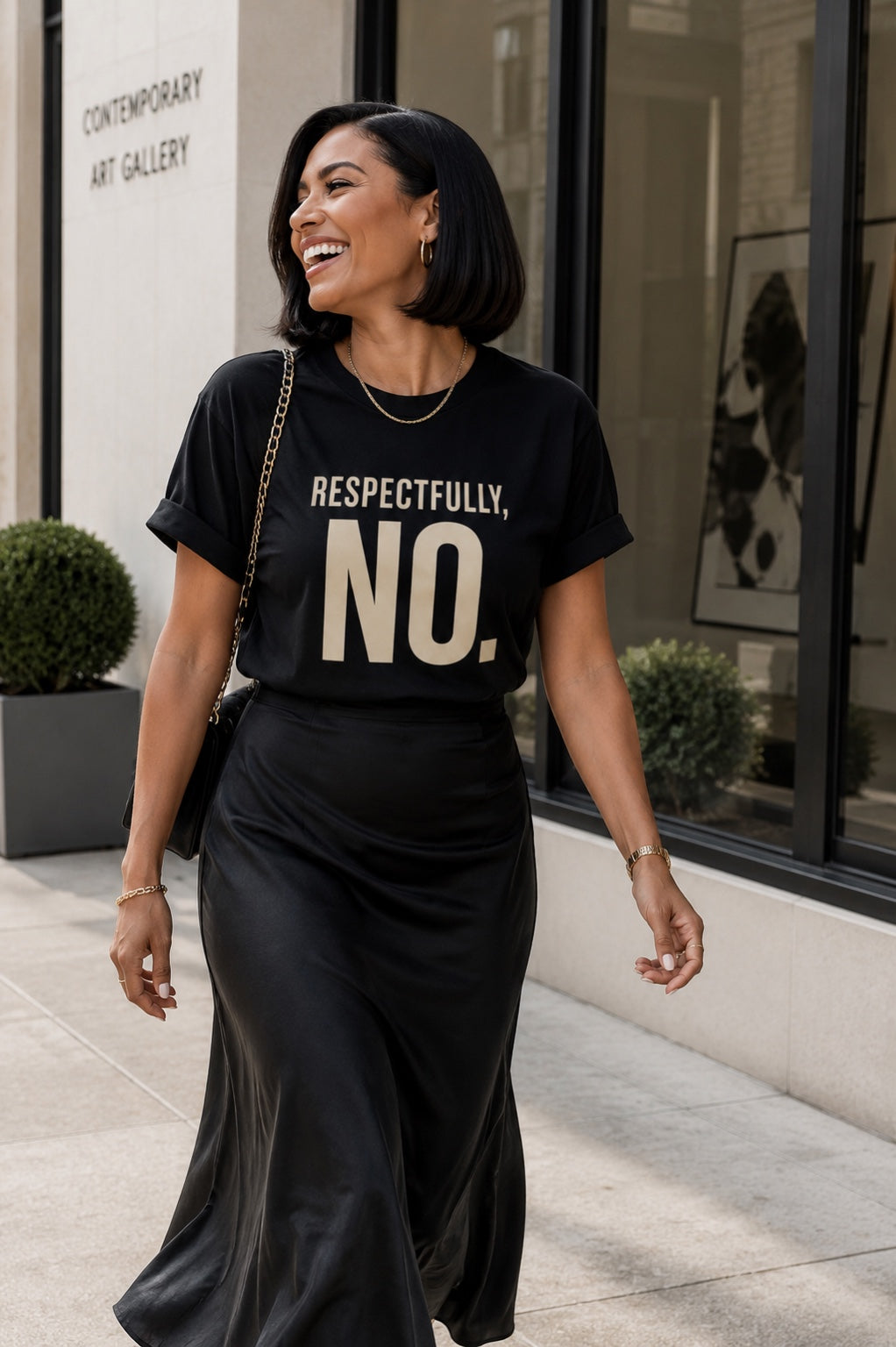 Woman laughing outside an art gallery in the Respectfully, No. black statement tee and satin skirt.