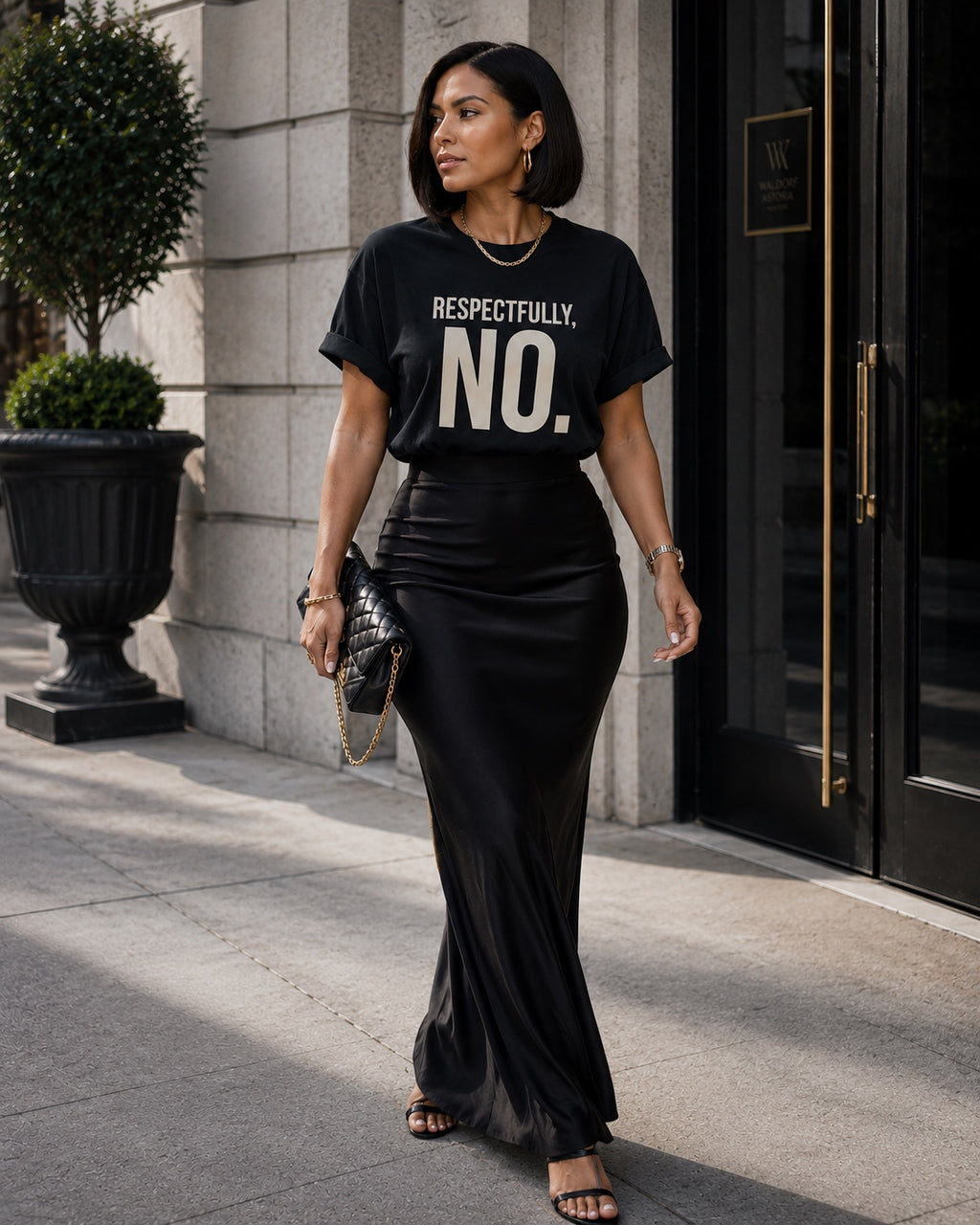 Woman wearing the Respectfully, No. black statement tee styled with a black satin maxi skirt.