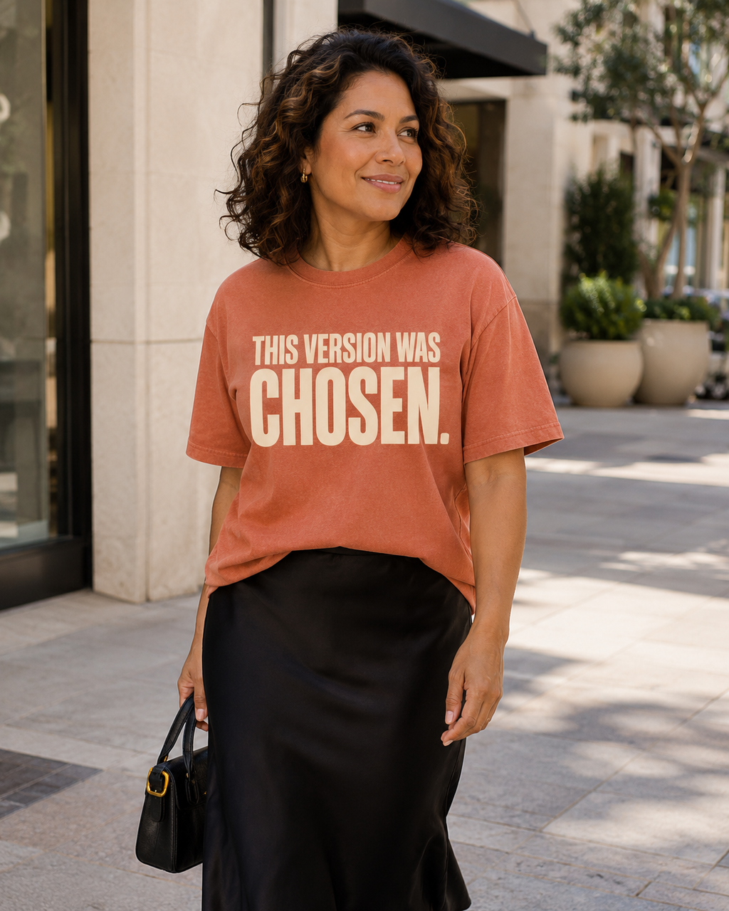 Hispanic woman wearing the This Version Was Chosen statement tee in terracotta with cream typography
